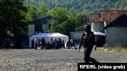 Një pjesëtar i njësive speciale të Policisë së Kosovës ecën pranë disa serbëve, që po protestojnë në Jarinjë më 26 shtator. 