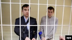 Aleksandr Aleksandrov (right) and Yevgeny Yerofeyev stand in a defendants' cage as they attend a court hearing in Kyiv in September.