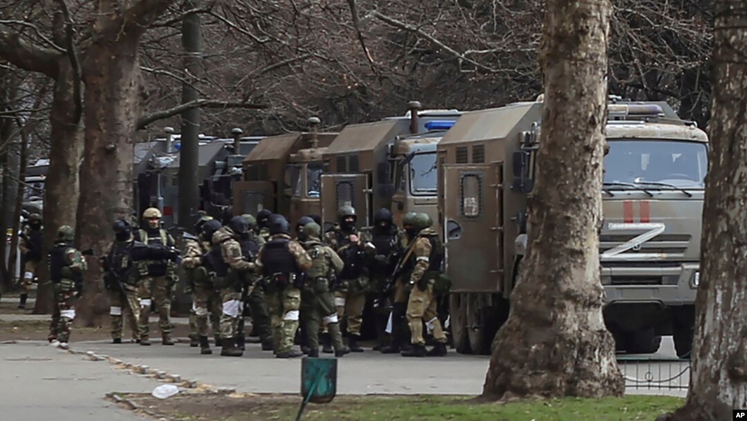 Russian soldiers stand next to their trucks during a rally against Russian occupation in Kherson on March 7.