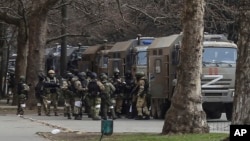 Russian soldiers stand next to their trucks during a rally against Russian occupation in Kherson on March 7.