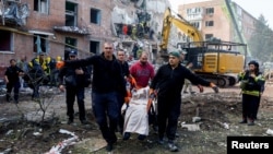 People carry a casualty as emergency services work to rescue residents from under the debris at the site of an apartment building hit by a Russian missile strike in the town of Pryluky, in Ukraine's Chernihiv region on October 7.