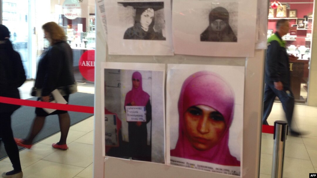 People walk past an information banner with the photos of terrorism suspects in a department store in the Russian Black Sea resort of Sochi on January 18.
