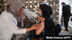 یک کارمند صحی در حال تطبیق واکسین ویروس کرونا برای یکی از شهروندان در کابل