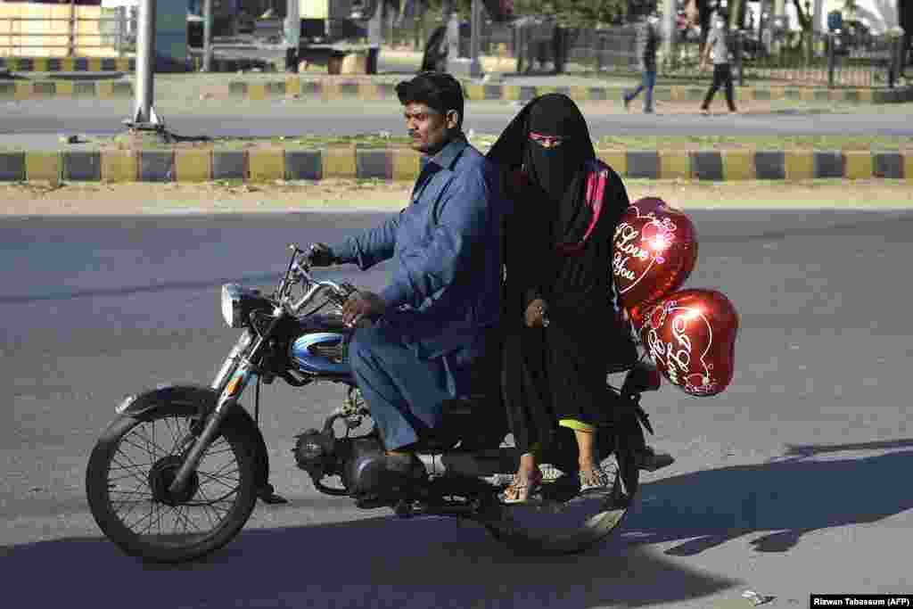 A woman carries a heart-shaped&nbsp;balloon&nbsp;while sitting with her husband on a motorbike in Karachi, Pakistan, on February 14. (AFP/Rizwan Tabassum)