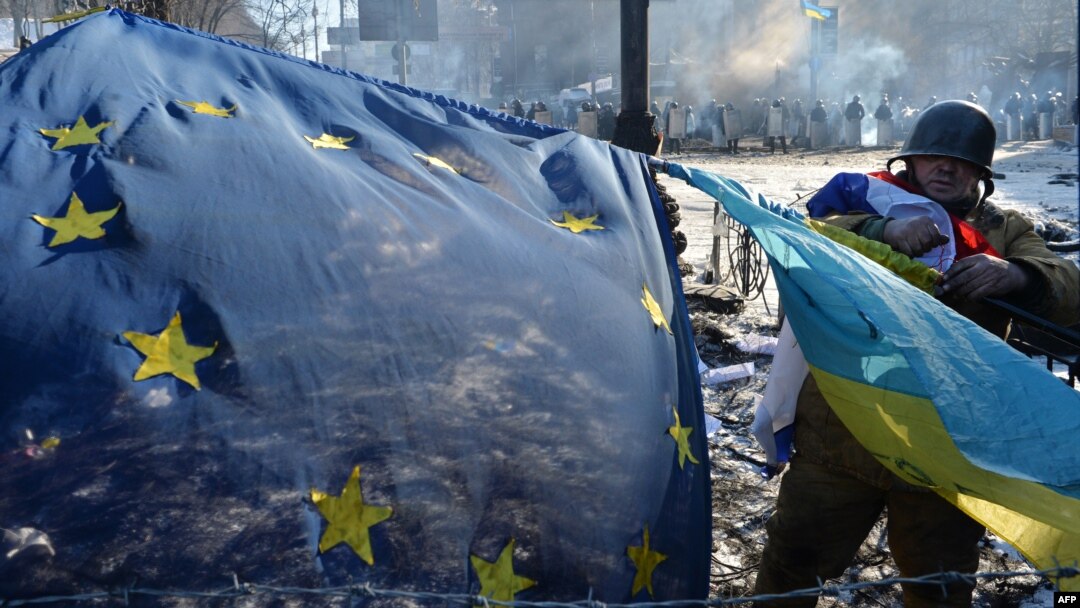 An antigovernment opposition activist places European Union and Ukrainian flags side by side at a barricade in the Ukrainian capital of Kyiv on February 2 as tens of thousands of protesters rallied to demand President Viktor Yanukovych resign.