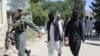 A member of the Afghan security forces escorts alleged Islamic State fighters being presented to the media at the police headquarters in Jalalabad on May 29.