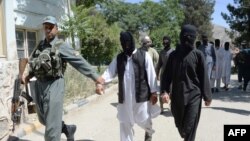 A member of the Afghan security forces escorts alleged Islamic State fighters being presented to the media at the police headquarters in Jalalabad on May 29.