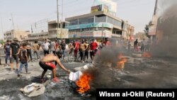 A demonstrator burns tires during a curfew, two days after the nationwide anti-government protests turned violent, in Baghdad, October 3, 2019