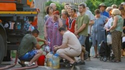 Residents wait in line to collect water delivered by a tank truck in Donetsk on July 29.