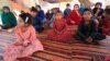 Internally displaced children listen to UNICEF campaigners talk about the coronavirus at a makeshift camp in Jalalabad on June 22.
