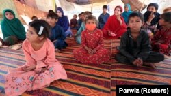 Internally displaced children listen to UNICEF campaigners talk about the coronavirus at a makeshift camp in Jalalabad on June 22.