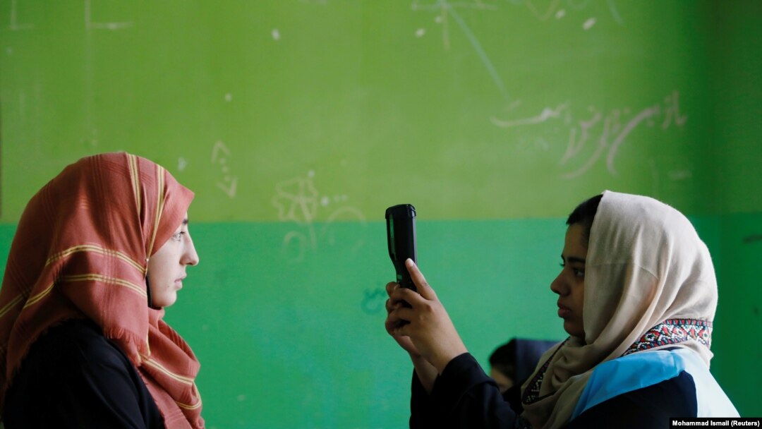 Alegătoare si funcționară electorală folosind un dispozitiv biometric in alegerile prezidențiale din Afganistan.