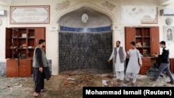 Men inspect the site of a blast inside a mosque in Kabul on June 12.