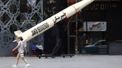 A woman walks next to a symbolic mockup of an Iranian missile in Tehran. 