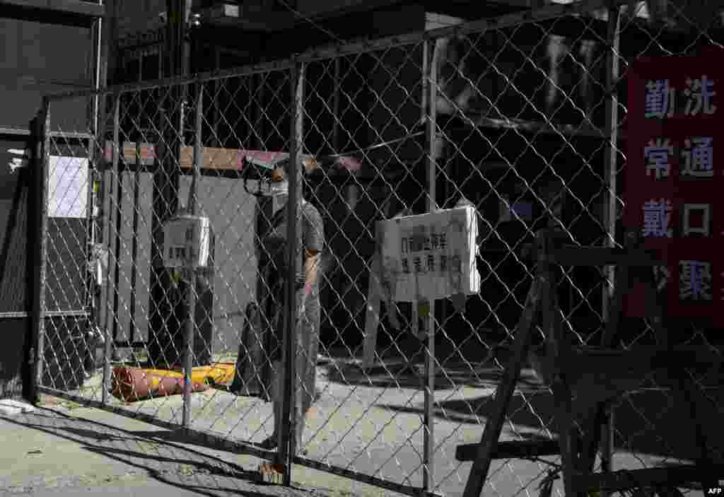 Жінка стоїть за огорожею, поки чекає доставки товарів, які вона замовила в інтернеті в житловому районі Іланьюань, який знаходиться в закритому режимі після нового спалаху коронавірусу COVID-19 поблизу закритого ринку Сінфаді, у Пекіні. Одинадцять житлових будинків на півдні Пекіна були закриті через нові випадки коронавірусу, пов&#39;язані з м&#39;ясним ринком Сінфаді, заявили чиновники 13 червня 2020 року