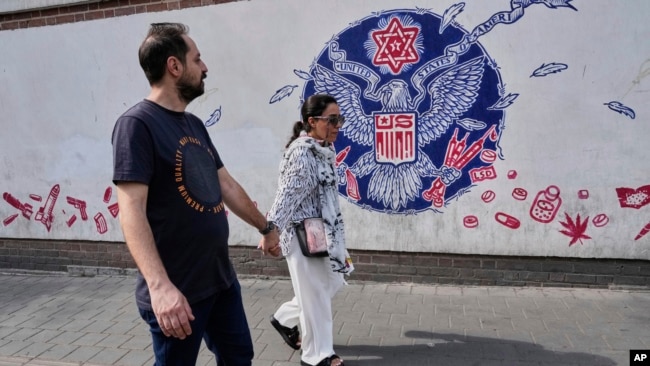 زوج جوانی در حال عبور از مقابل سفارت سابق آمریکا در تهران