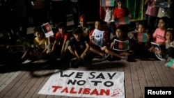 Children sit in front of a banner reading "We say no to Taliban" as Afghan migrants demonstrate against the Taliban takeover of Afghanistan on the island of Lesbos, Greece, on August 16.