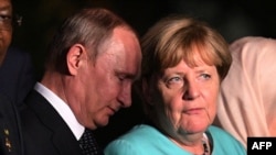 German Chancellor Angela Merkel talks to Russian President Vladimir Putin (left) as G20 leaders and their spouses walk for a group picture prior to a banquet at the G20 summit in Hangzhou, China, on September 4.