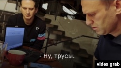 Христо Грозев (вляво) наблюдава как руският опозиционер Алексей Навални говори с човека от руските служби, който се е опитал да го убие с Новичок. Германия, 2021 г. Стоп кадър от видео.