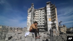 Palestinski dečak sedi ispred stambene zgrade uništene u izraelskom napadu na Rafu, Pojas Gaze, 9. mart 2024.