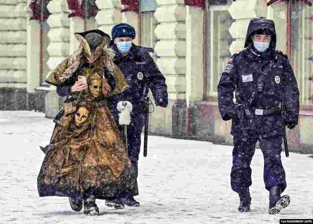 Two police officers escort a woman in a carnival costume in Moscow. (AFP/Yury Kadobnov)