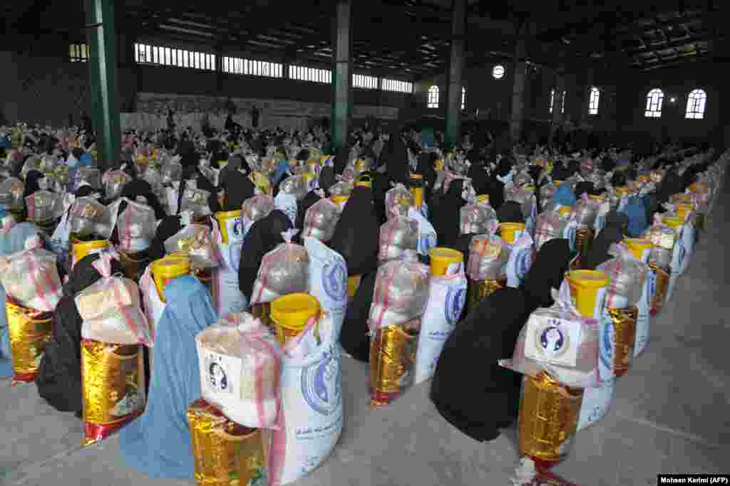 After: Afghan women sit behind packages of food aid in the western city of Herat in March 2025.
