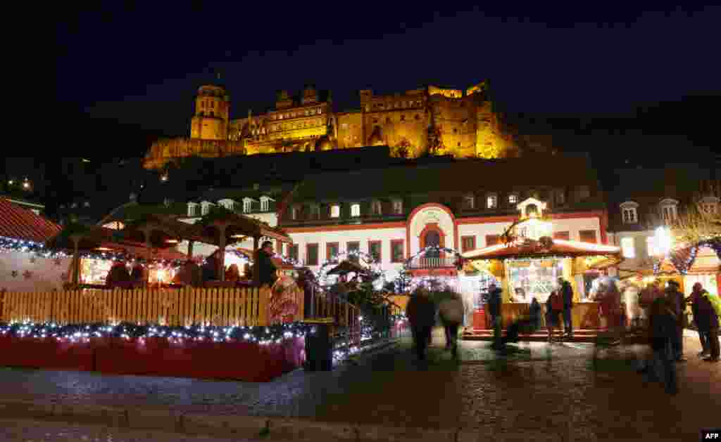 Oamenii vizitează târgul de Crăciun, cu Castelul Heidelberg în fundal, în Heidelberg, vestul Germaniei, pe 16 decembrie 2025.