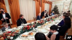 Vladimir Putin, centru-dreapta, la masa de Crăciun alături de familii ale militarilor morți în războiul din Ucraina, la reședința de stat Novo-Ogariovo, Rusia, 6 ianuarie 2024. (Gavriil Grigorov/Sputnik/Kremlin Pool Photo via AP)