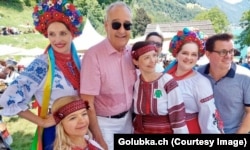 Президент Швейцарії Гі Пармелен позує із людьми у традиційних костюмах різних народів і країн, у тому числі України. Національне свято Швейцарії, історичний луг Рютлі, 1 серпня 2026 року