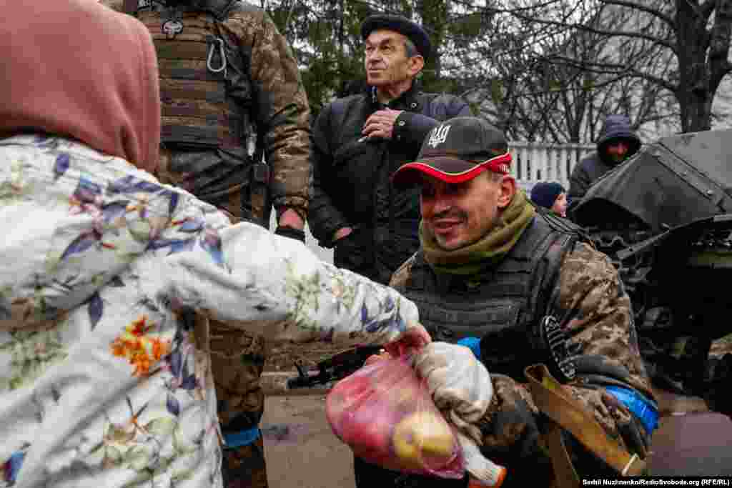 Дівчинка дарує військовому ЗСУ пакет яблук після звільнення українськими військовими її села Бахмач, що на Чернігівщині, у квітні 2022 року