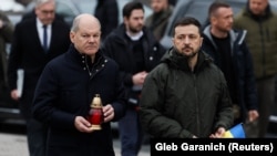 Ukrainian President Volodymyr Zelenskiy (right) and German Chancellor Olaf Scholz visit a makeshift memorial to fallen soldiers on Independence Square in Kyiv on December 2. 