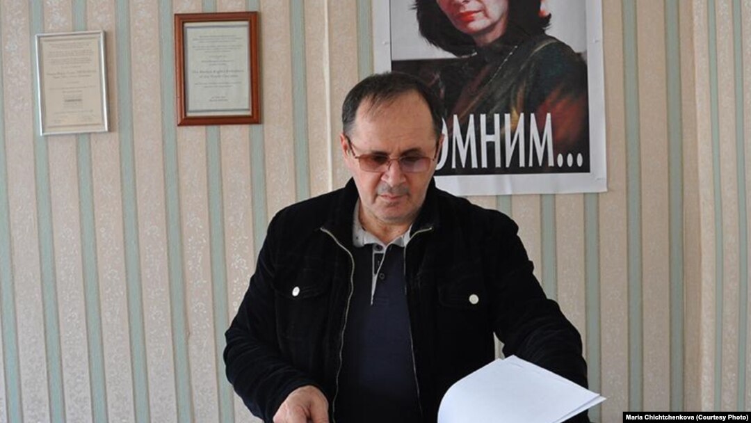 Chechen rights activist Oyub Titiyev in Memorial's Grozny office, with a portrait of slain activist Natalya Estemirova on the wall behind him