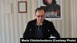 Chechen rights activist Oyub Titiyev in Memorial's Grozny office, with a portrait of slain activist Natalya Estemirova on the wall behind him