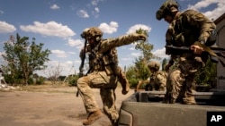 Ukrainian soldiers jump from a pickup truck to take up positions at the front line in the Mykolayiv region. 