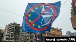 Steag anti-UE și anti-NATO la un protest provocat de planul ginerelui lui Donald Trump de a construi un mare hotel în centrul Belgradului. Ostilitatea față de Occident, mărită de bombardamentele din 1999, continuă să fie parte a culturii politice sârbe.