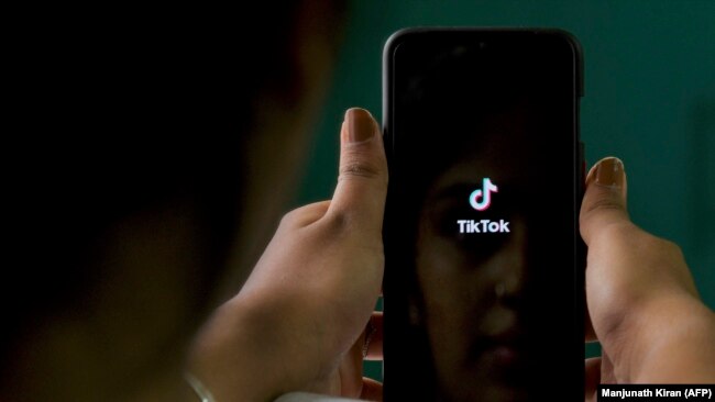 Një përdoruese duke hapur aplikacionin TikTok në telefonin e saj të mençur mobil.
