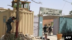 Afghan security personnel gather as the body of an insurgent lies at the entrance of the Ghazni court.