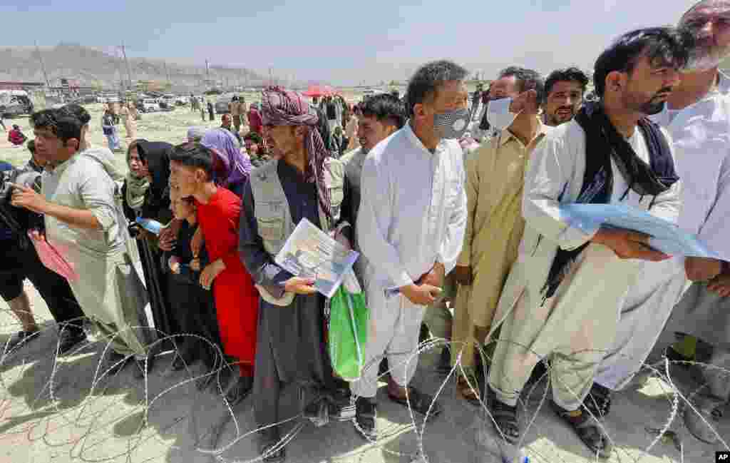 A kabuli repülőtéren várakozó tömegben egy afgán férfi mutatja azt az oklevelet, amelyet az amerikai csapatoknak végzett munkájáért kapott
