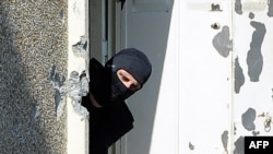 A hooded French policeman looks outside the window on March 23 as he investigates the flat where self-professed Al-Qaeda militant Mohamed Merah, 23, was living in Toulouse.