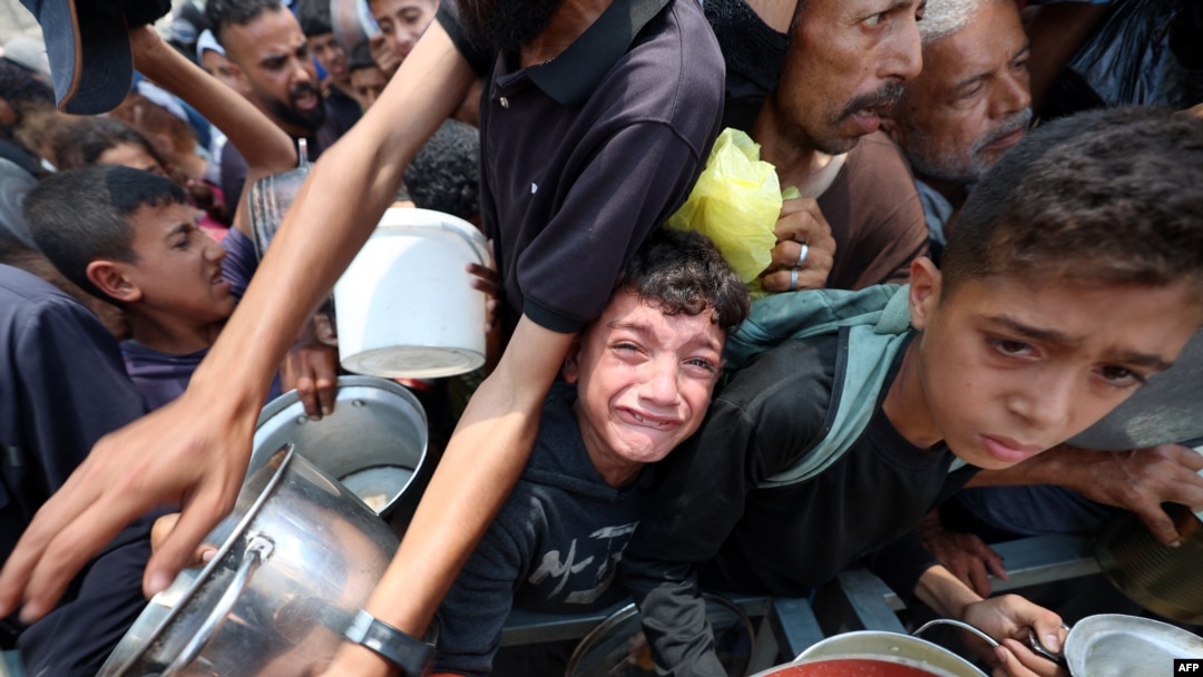 Copiii stau la coadă pentru mâncare la un punct de distribuție din Nuseirat, în centrul Fâșiei Gaza - 11 iunie 2025.