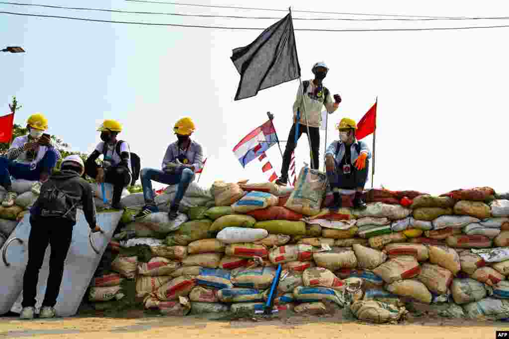 Protesters sit on a makeshift barricade erected to deter security forces during demonstrations against the military coup in Yangon&#39;s Hlaing Tharyar township on March 14, 2021.