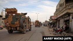 Turkish military vehicles drive in a convoy headed for the south of Idlib Province as they pass by the town of Atareb on February 3.