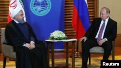 Eýranyň prezidenti Hassan Rouhani (Ç) rus kärdeşi Wladimir Putin bilen gürleşýär. Kingdao, 9-njy iýun, 2018. 