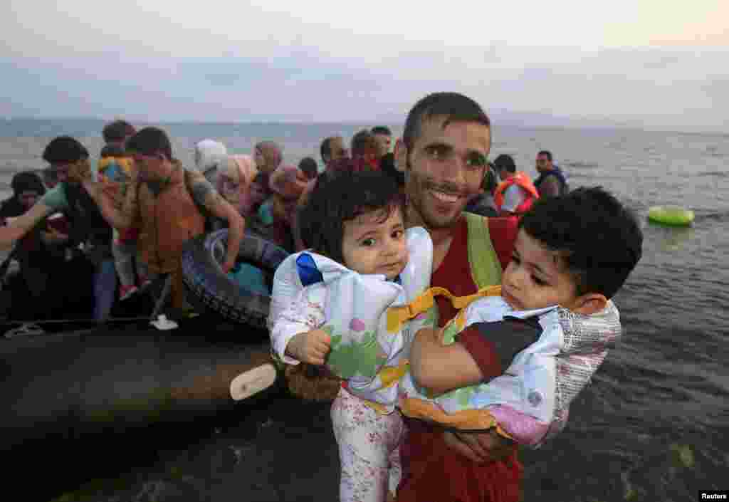 A Syrian refugee from Kobani holds two children as he jumps off a small boat onto a beach on the Greek island of Kos after crossing the Aegean Sea from Turkey. The UNHCR called on Greece to take control of the "total chaos" on its Mediterranean islands, where thousands of migrants have landed. About 124,000 have arrived this year by sea, many via Turkey. (Reuters/Yannis Behrakis)