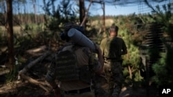 Військовослужбовець ЗСУ несе снаряд до гаубиці на околиці Лиману, Україна, 15 серпня 2023 року