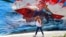 A woman in Tehran walks past an anti-US and anti-Israel mural depicting missiles hitting an aircraft carrier. 