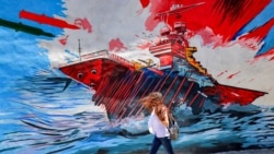 Žena u Teheranu prolazi pored antiameričkog i antiizraelskog murala koji prikazuje rakete koje pogađaju nosač aviona, 26. maj 2026.