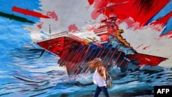 Žena u Teheranu prolazi pored antiameričkog i antiizraelskog murala koji prikazuje rakete koje pogađaju nosač aviona, 26. maj 2026.