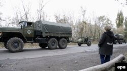 Жінка пропускає колону бойовиків угруповання «ДНР», які відводять артилерію калібром до 100 мм від лінії зіткнення в районі села Зелене, Донецької області. 28 жовтня 2015 року