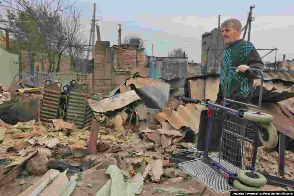 Një banor lokal qëndron pranë një ndërtese të shkatërruar pas një zjarri në pyll në fshatin Syrotyne në rajonin lindor të Ukrainës Luhansk. (Shërbimi për Shtyp i Qeverisë Ukrainase përmes Reuters / Sergii Kharchenko)